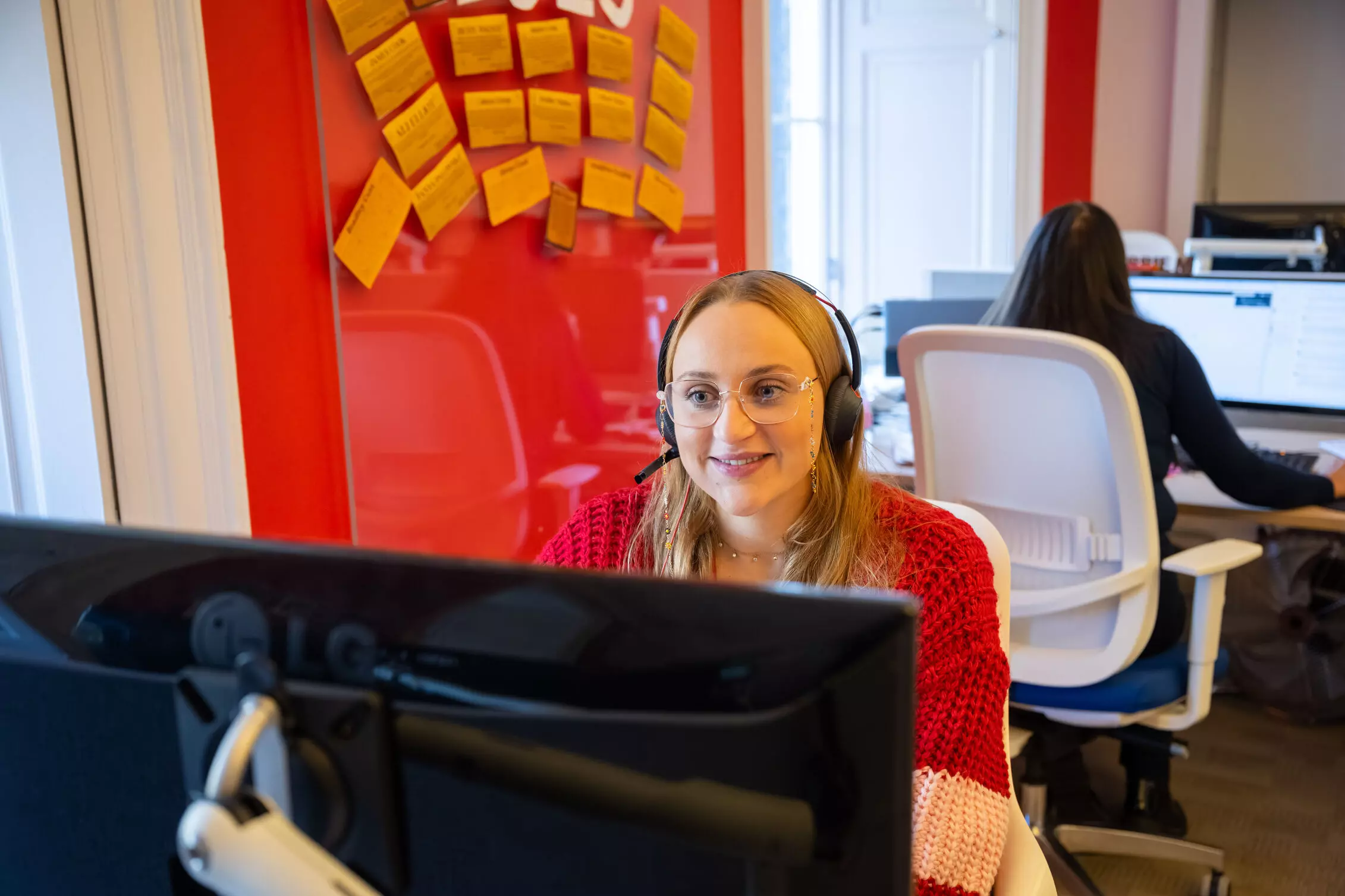 Employees sitting on a stage in red jackets 