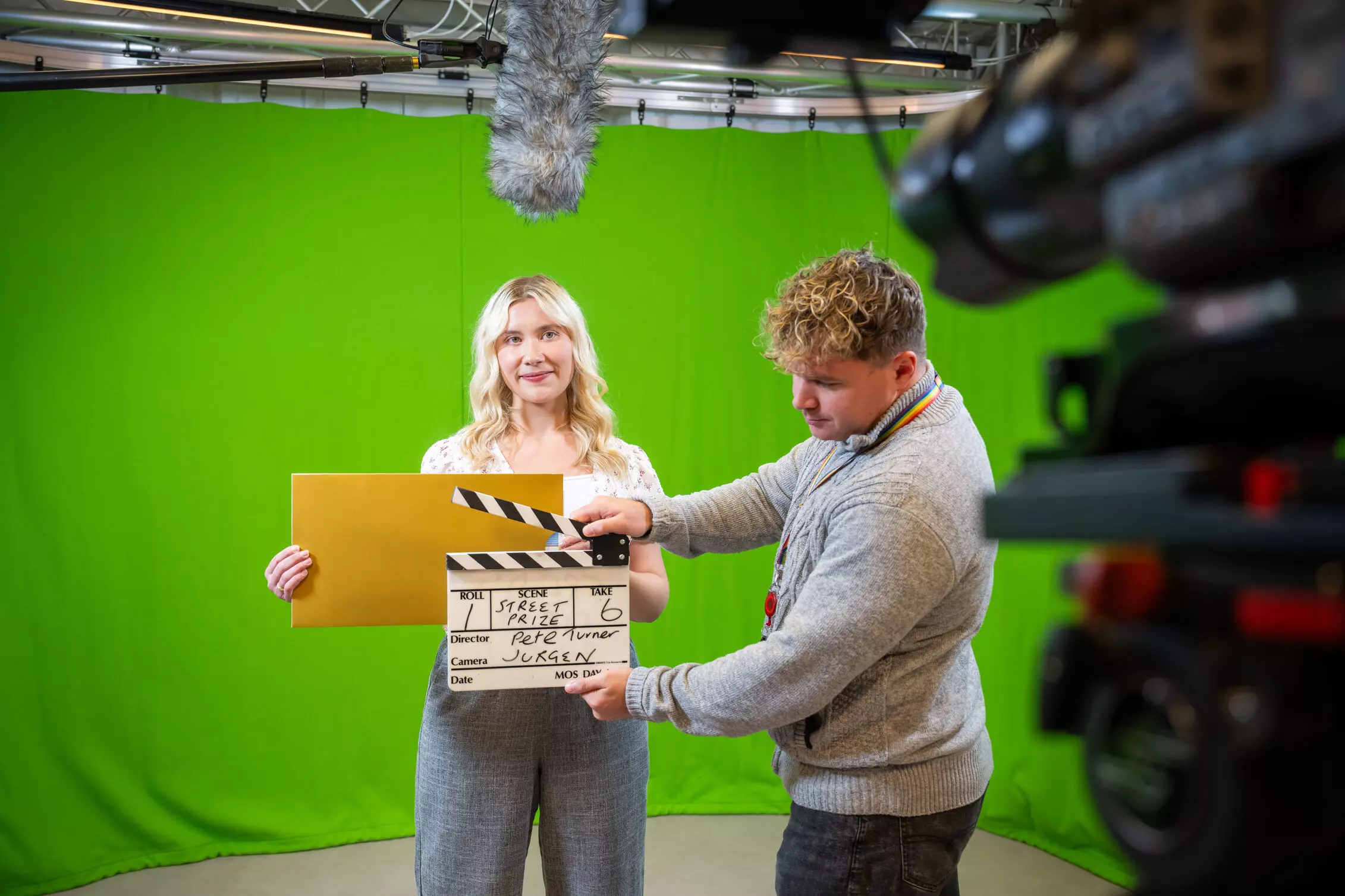 A group of winners, holding cheques, outside under umbrellas