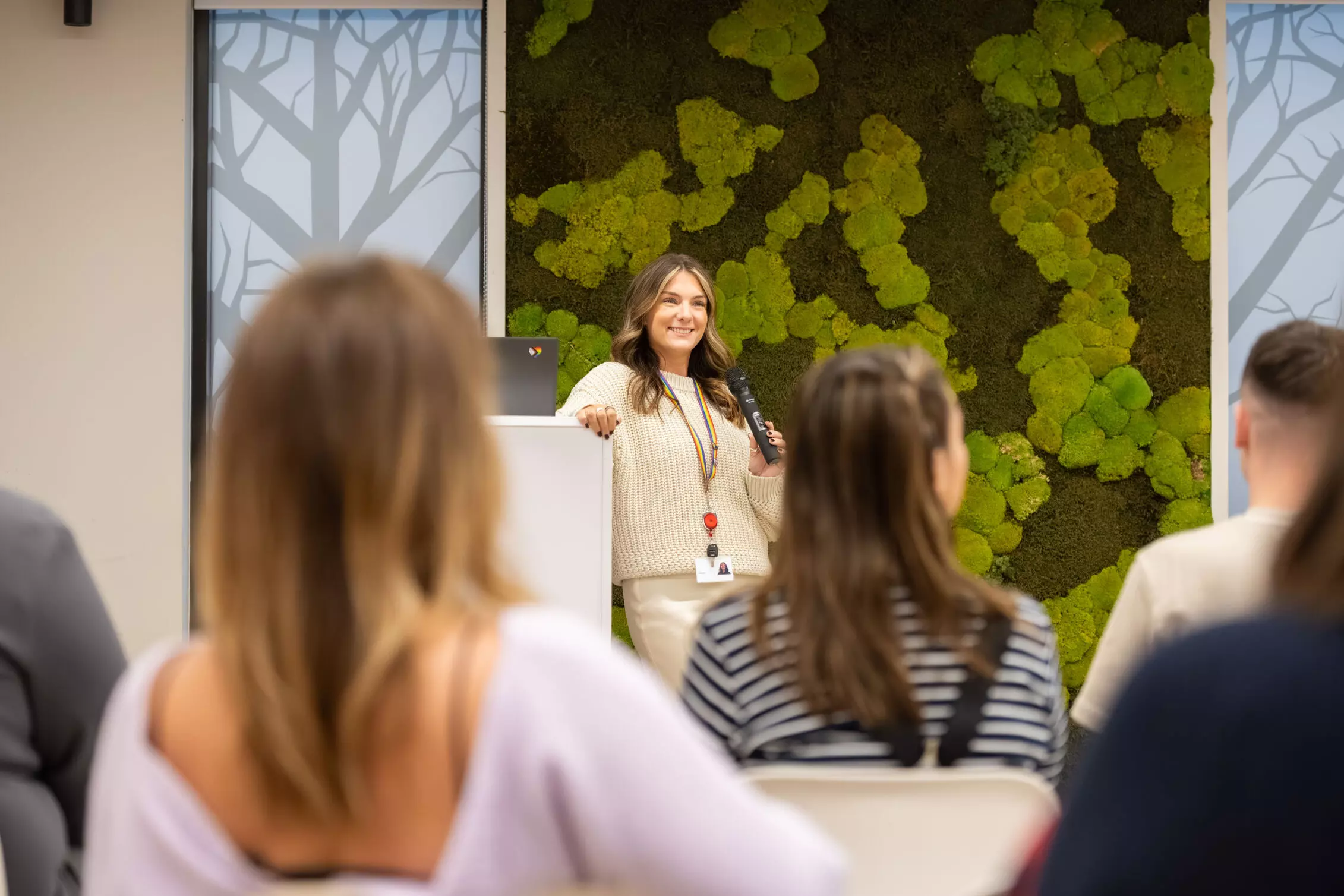 Employees outside. sitting on a wall, holding gold cheques