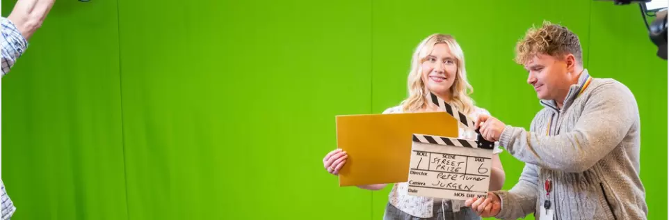 An employee sitting at a desk in the office, with a laptop and headphones on.