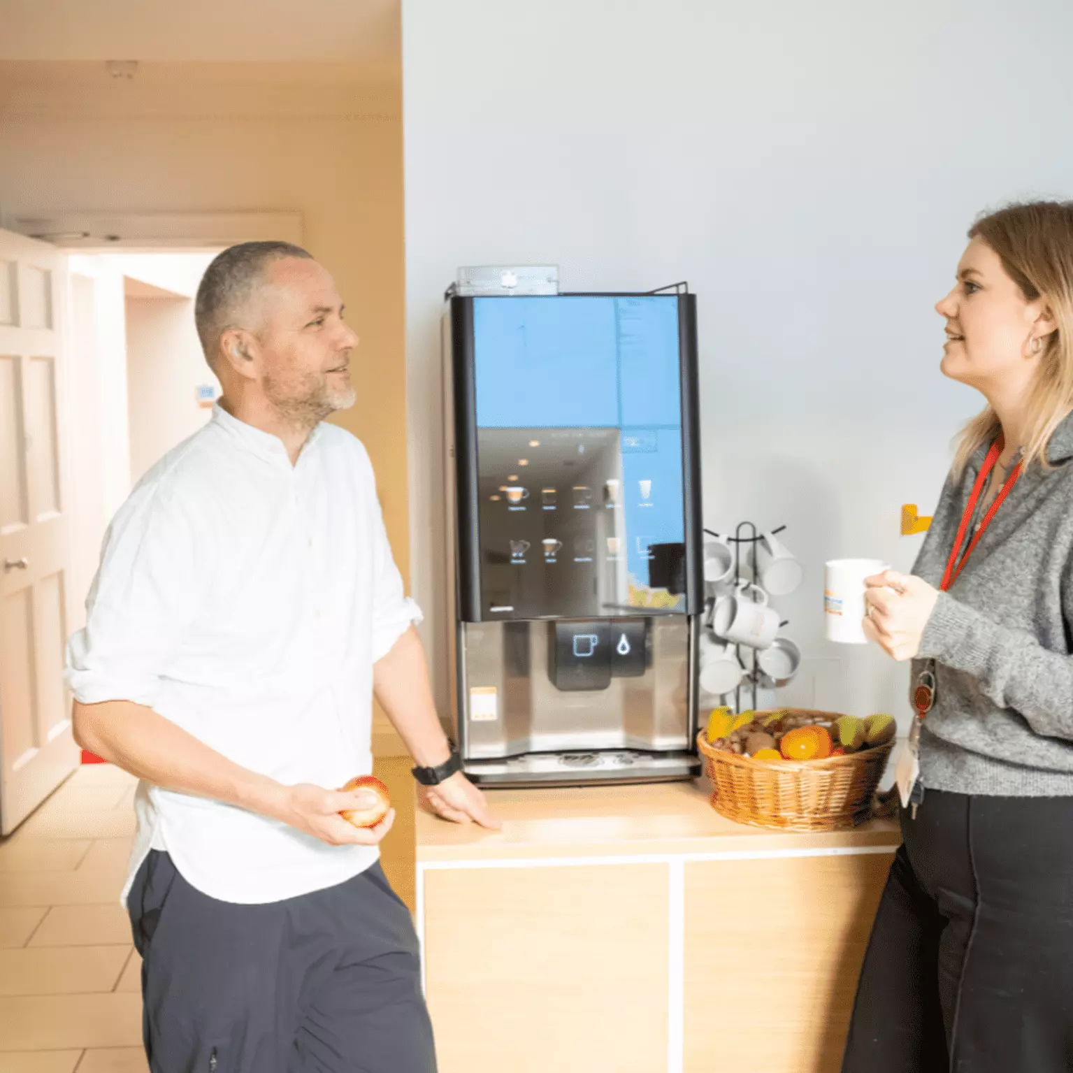 Two Employees standing next to a coffee machine having a conversation 