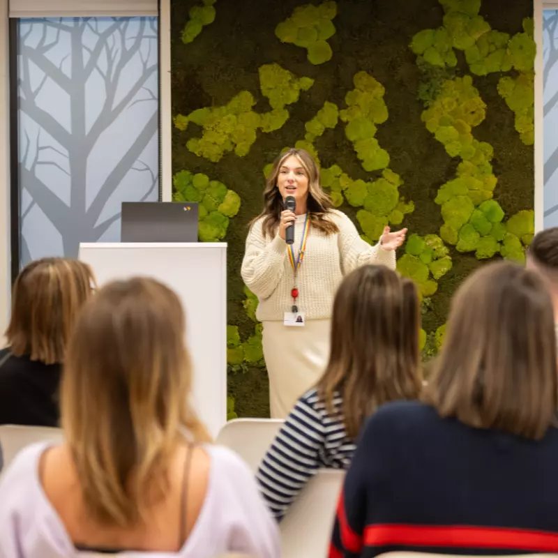 An Employee presenting to other colleagues, using a microphone