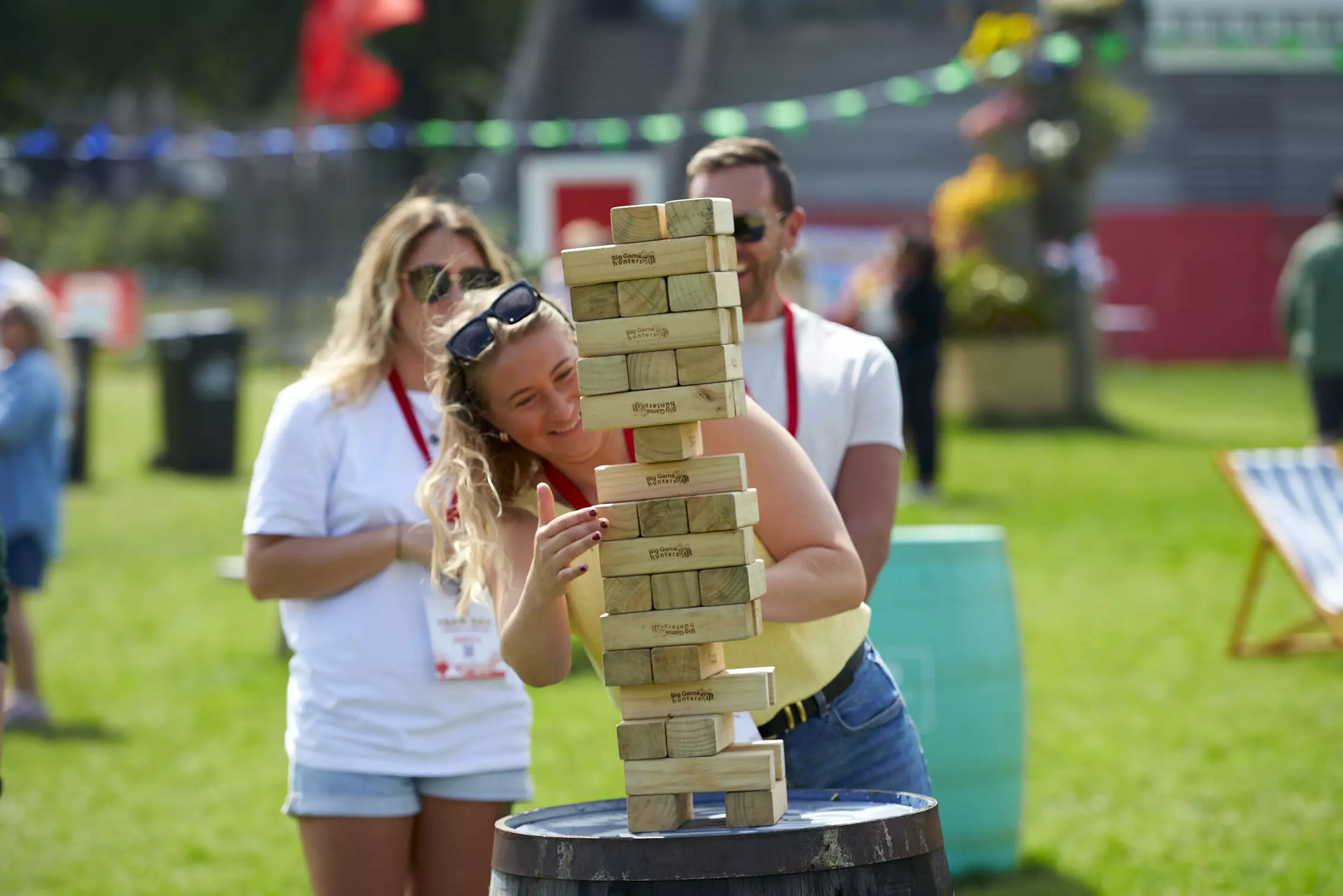 Woman playing jenga, looked on by two other colleagues 