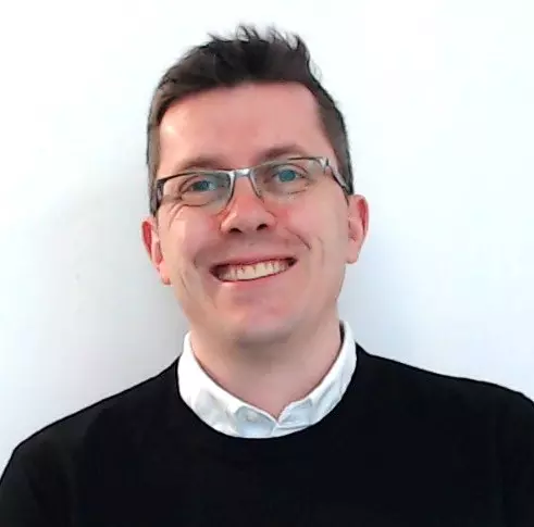 Headshot of an employee standing in front of a grey background
